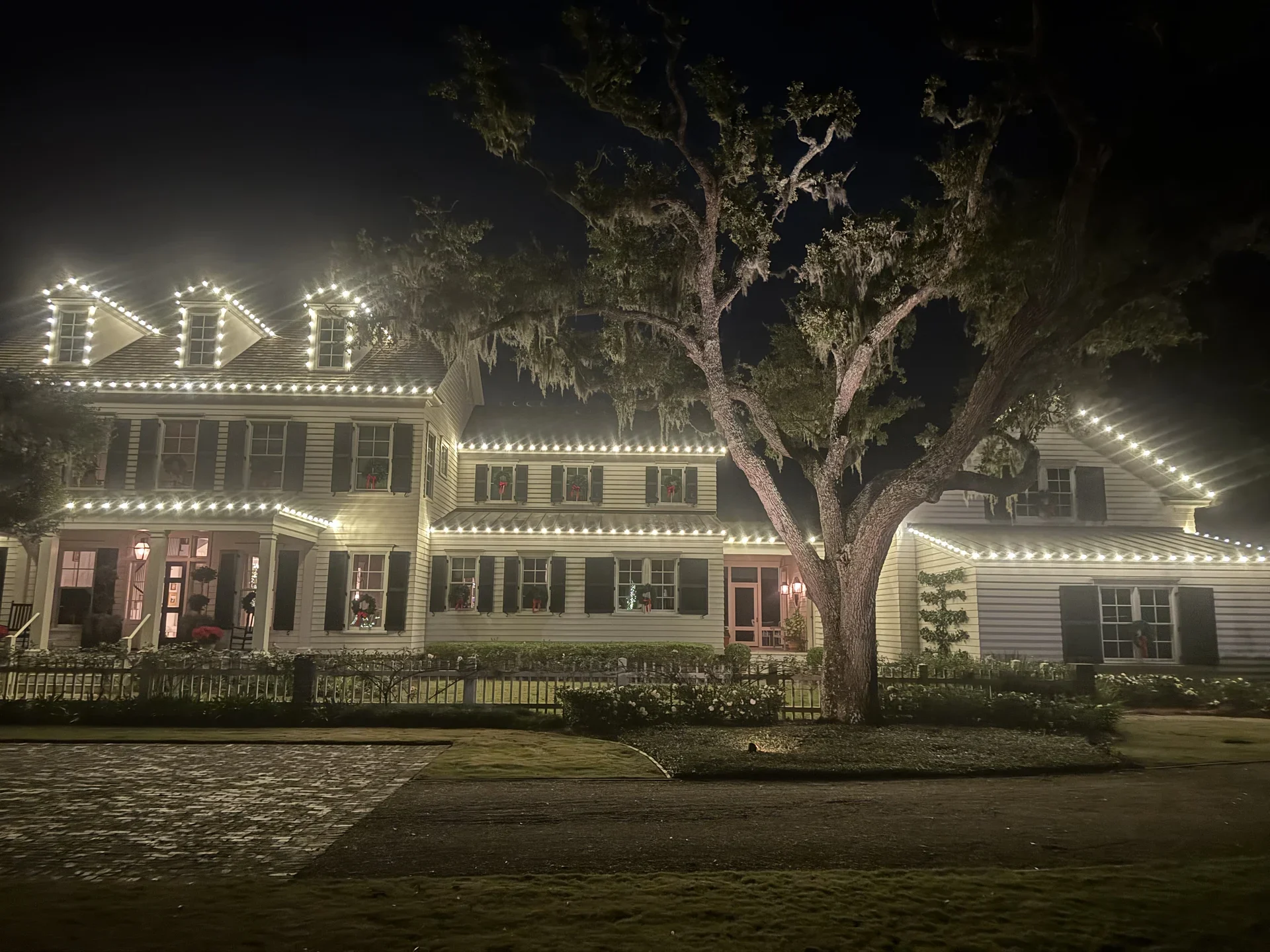 A two-story home with warm white Christmas lights tracing its roof